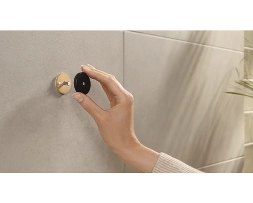 Person befestigt einen runden Wandhaken an der Wand