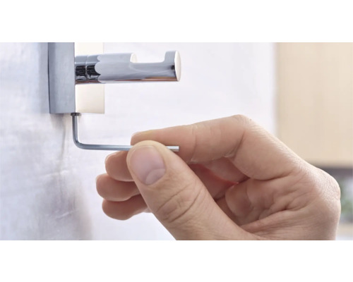 Hand befestigt einen Bademantelhalter mit einem Inbusschlüssel