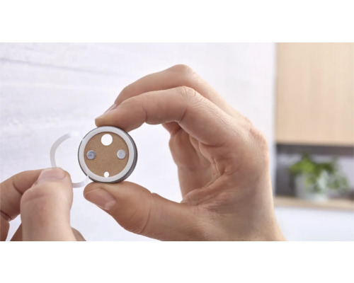 Eine Person hält eine Magnethalterung für Rauchmelder in der Hand.