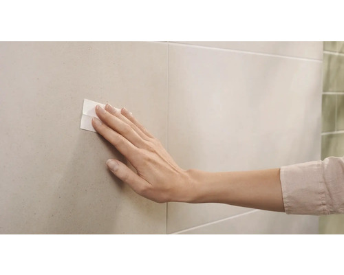 Hand, die ein doppelseitiges Klebeband auf Fliesen drückt