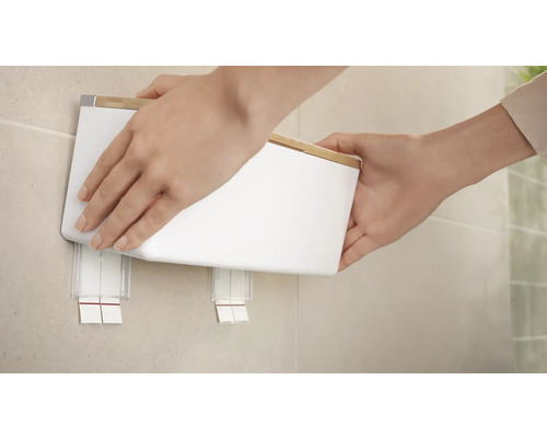 Eine Person befestigt einen weißen Wandabfallbehälter an der Wand.