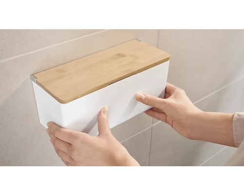 Person montiert eine weiße Wandbox mit Bambusdeckel an einer Wand