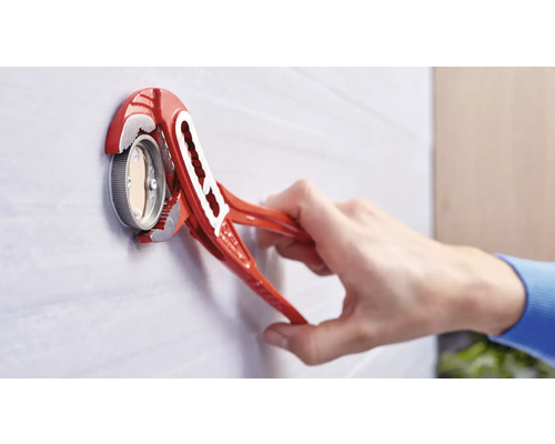 Eine rote Wasserpumpenzange wird verwendet, um ein Metallventil an einer Wand zu befestigen.