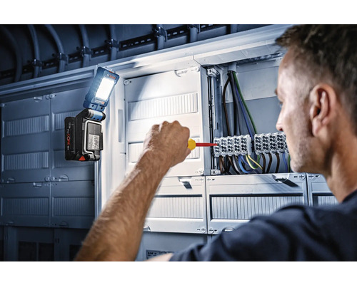 Ein Elektriker arbeitet an einem Verteilerkasten mit einer Bosch Arbeitsleuchte.
