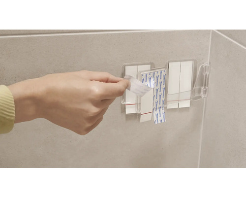 Person entfernt Schutzfolie von Klebestreifen an einer Wandbefestigung