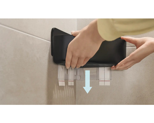 Person befestigt einen schwarzen Wandorganizer an der Wand