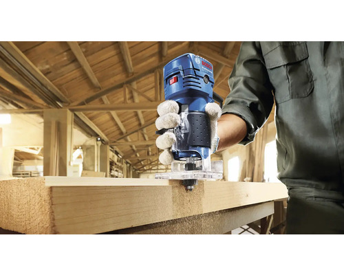 Eine Person verwendet eine Oberfräse von Bosch Professional an einem Werkstück aus Holz.