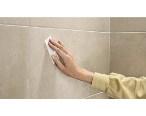 Eine Person reinigt Fliesen mit einem Reinigungstuch.