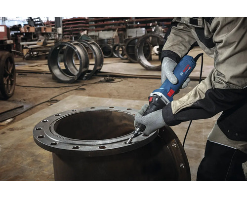 Ein Mann benutzt einen Geradschleifer an einem Metallrohr.