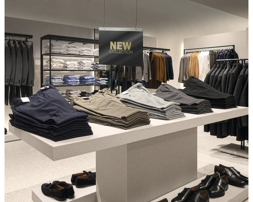 Bekleidungsgeschäft mit Herrenbekleidung: Hosen und Schuhe auf einem Tisch präsentiert, Kleiderständer im Hintergrund.