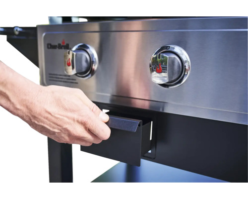 Detailaufnahme eines Grills mit Bedienelementen und ausziehbarer Schublade, die von einer Hand geöffnet wird