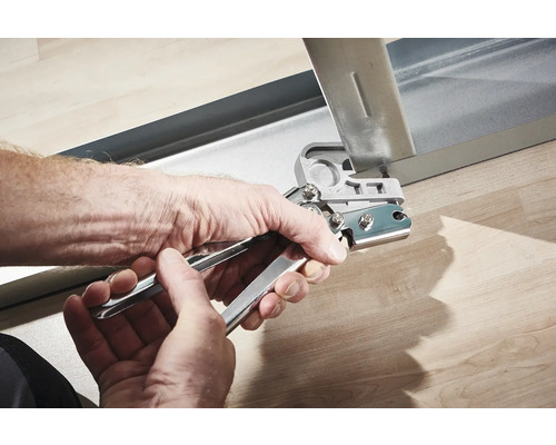 Hände benutzen eine Lochzange an einem Metallprofil