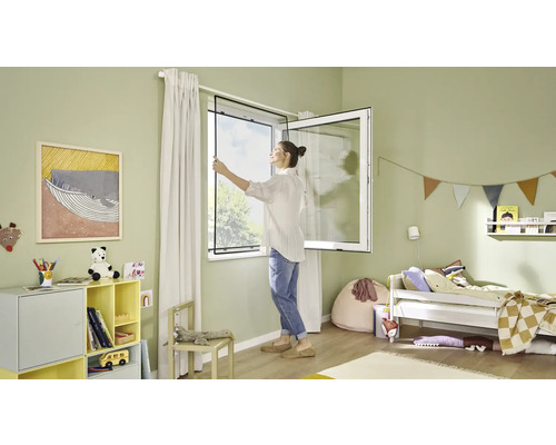 Frau montiert Insektenschutzgitter am Fenster im Kinderzimmer