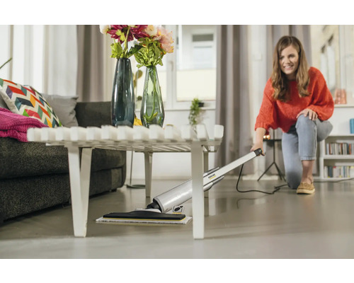 Frau reinigt Boden mit Kärcher Hartbodenreiniger unter Couchtisch