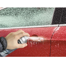 Eine Person sprüht Enteisungsspray auf einen vereisten Autogriff.
