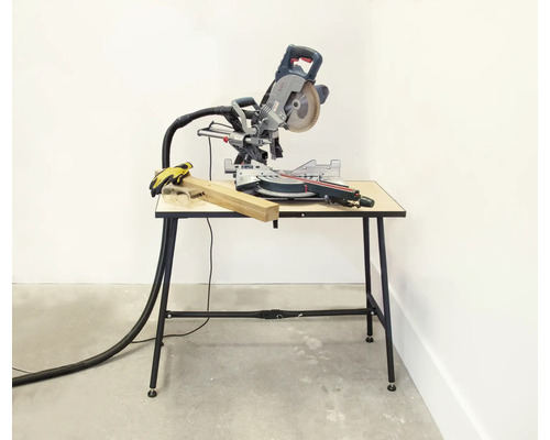 Kapp- und Gehrungssäge auf einem Arbeitstisch mit einem Stück Holz und Schutzhandschuhen