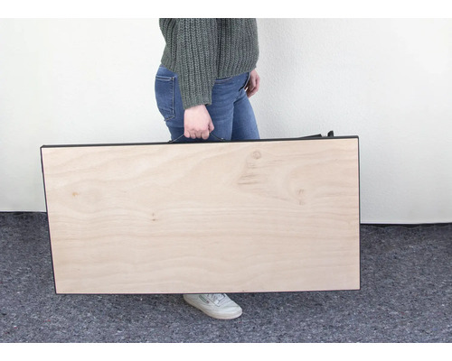 Person trägt eine Tischplatte mit Tragegriff