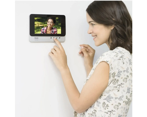 Frau bedient Philips Türsprechanlage an der Wand