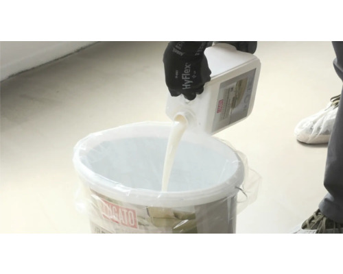 Eine Person giesst Flüssigkeit aus einem Behälter in einen Eimer.