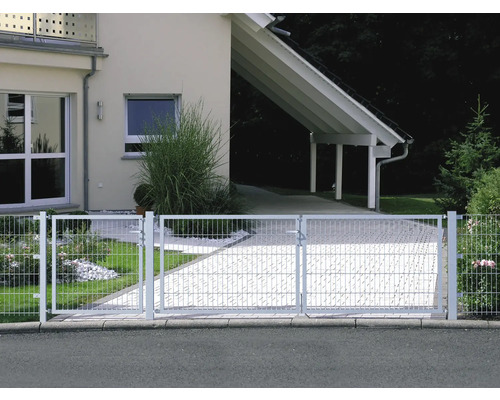 Metallzaun vor einem Wohnhaus mit gepflasterter Auffahrt