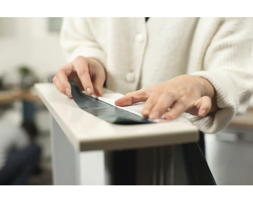 Eine Person bringt eine selbstklebende Folie auf eine Oberfläche auf.