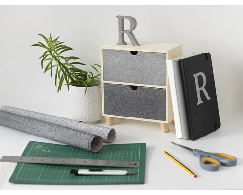 Dekorationsszene mit Kommode, Pflanze im Topf, Notizbüchern, Dekorfolie, Schneidebrett und Werkzeugen