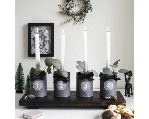 Adventsgesteck mit vier Kerzen und Dekorationen auf einem dunklen Holztablett.