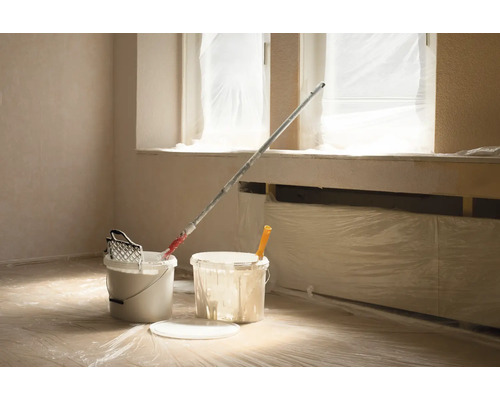 Raum mit Abdeckfolie, Farbeimern und Farbroller für Malerarbeiten