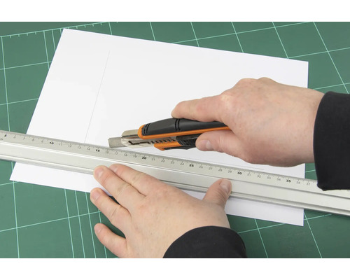 Papier schneiden mit einem Cuttermesser und einem Lineal auf einer Schneidematte