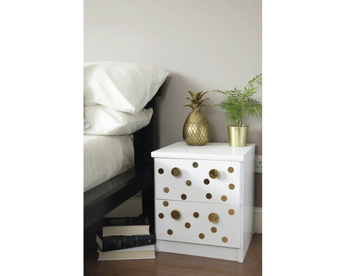 Nachttisch mit zwei Schubladen, goldenen Punkten und goldenen Griffen neben einem Bett