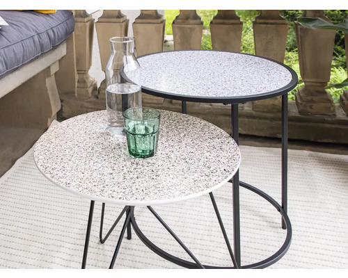 Zwei runde Beistelltische mit Getränkekaraffe und Glas auf einer Terrasse