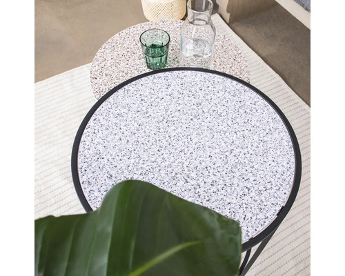Zwei runde Beistelltische mit Terrazzo-Tischplatten, ein Glas und eine Karaffe.