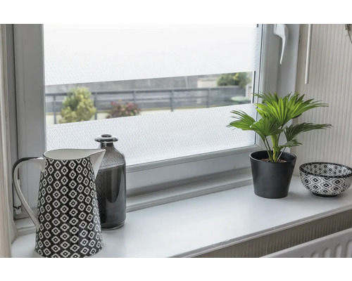 Dekorfolie auf einem Fenster mit Kaffeekanne, Flasche, Topfpflanze und Schale auf einem Fensterbrett