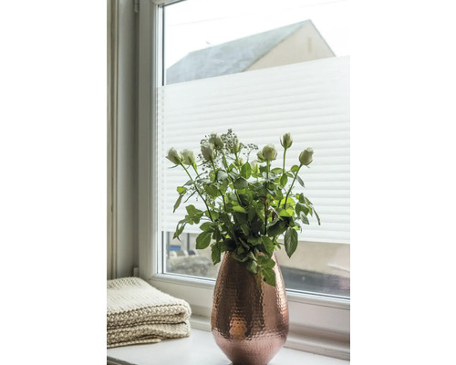 Blumenstrauß in einer Vase auf einer Fensterbank vor einem Plissee