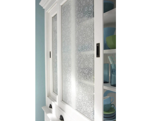 Detailaufnahme eines weißen Küchenschranks mit floral gemusterten Glastüren.