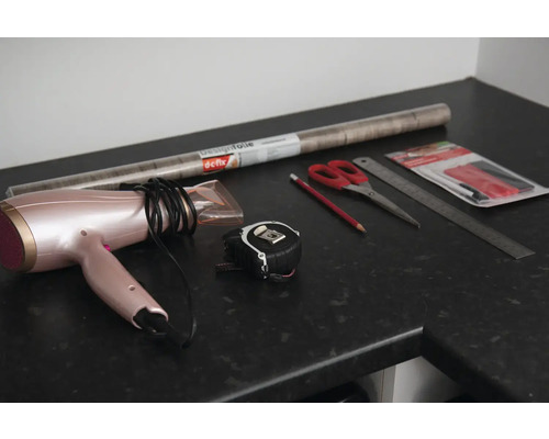 Dekofolie, Fön, Maßband, Schere, Bleistift, Lineal und Werkzeug zum Anbringen der Folie auf einer Arbeitsplatte