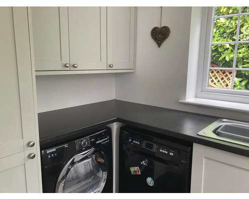 Waschküche mit Waschmaschine, Trockner, Spülmaschine, Waschbecken und Schränken