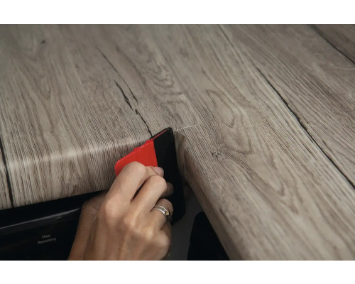 Anbringen einer Dekorfolie mit Rakel auf einer Holzoberfläche