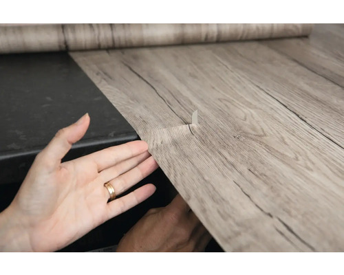 Selbstklebende Folie mit Holzoptik wird angebracht