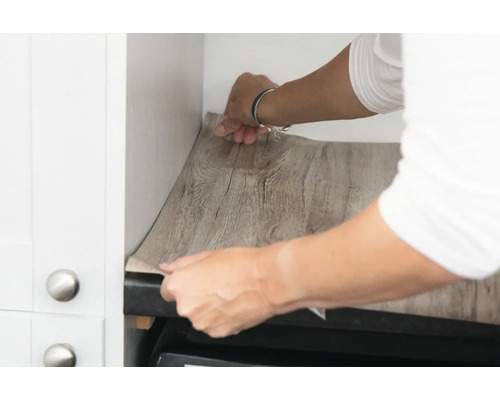 Person bringt Holzfolie in einer Küche an