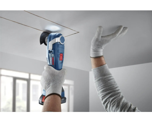 Person schneidet mit einem Multifunktionswerkzeug eine quadratische Öffnung in eine Decke.