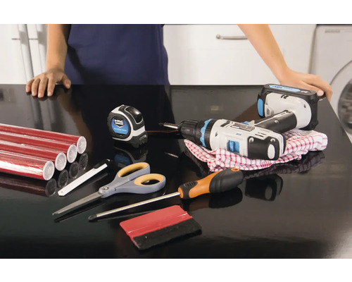 Werkfläche mit roter Möbelfolie, Akkuschrauber, Maßband, Schraubendreher, Schere und Rakel für die Anbringung