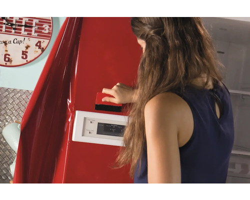 Frau bringt eine rote Möbelfolie mit einem Rakel auf einen Kühlschrank an.