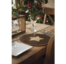 Festlich gedeckter Holztisch mit Geschirr, Besteck und Dekoration vor einem Weihnachtsbaum.