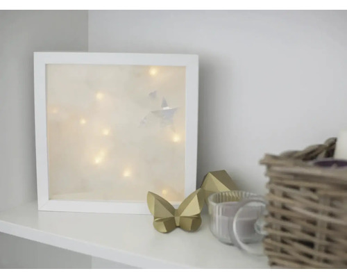 Dekorative Szene mit beleuchtetem Bilderrahmen, Schmetterling und Kerze