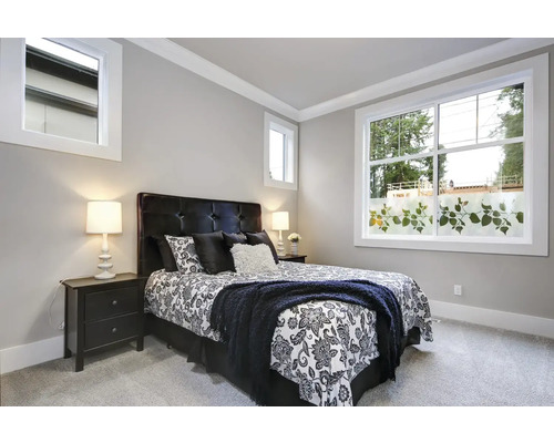 Schlafzimmer mit Bett, Nachttischen und Fenster mit Dekorfolie