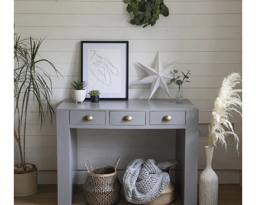 Dekoratives Interieur mit Konsole, Kunst, Pflanzen und Körben in einem hellen Raum.