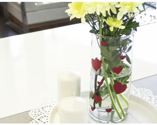 Dekoratives Arrangement mit Blumen, Herzchenvase und Kerzen