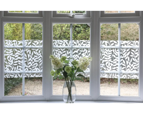 Fenster mit Sichtschutzfolie mit Pflanzenmuster und Blumenstrauß in Vase