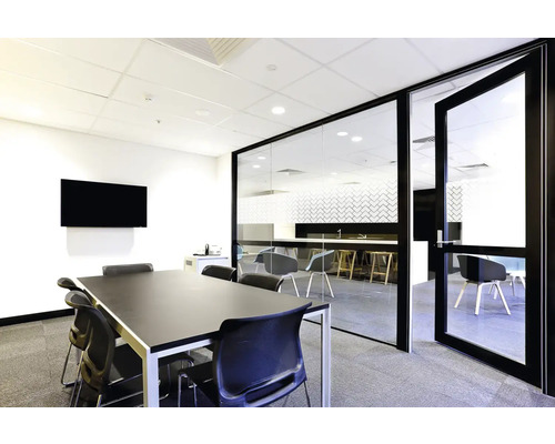 Konferenzraum mit Tisch, Stühlen, Bildschirm und Glastür